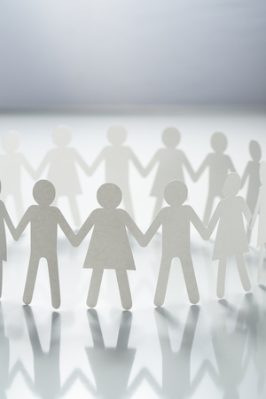 Circle of paper people holding hands on white surface. Community, union concept. Society and support.の写真素材