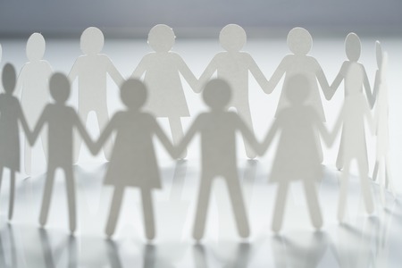 Circle of paper people holding hands on white surface. Community, union concept. Society and...
