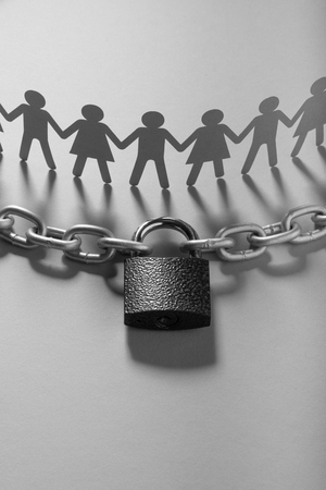 Human paper figures in front of metal chain and padlock on a white surface. Freedom, human rights,...