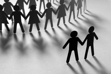 Black paper figure of male couple in front of a crowd of paper people holding hands on orange surface. Social movement, minorities, protest concept.の写真素材