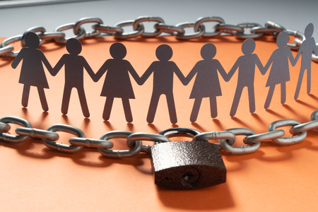 Human paper figures in front of metal chain and padlock on a red surface. Freedom, human rights, independence.の写真素材