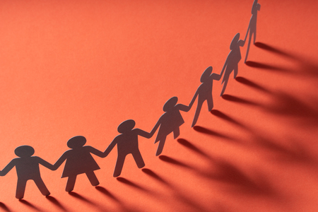 Paper people holding hands on red surface. Community, union concept. Society and support.の写真素材