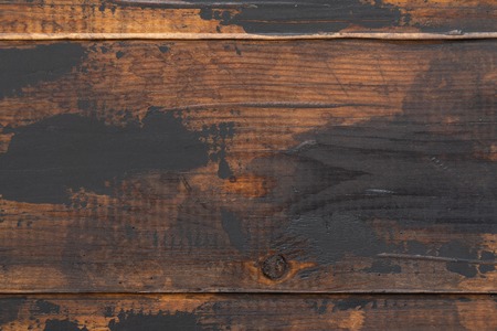 Old wooden surface background, scuffed boards with black paint stains.