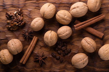 Walnuts, cinnamon, star anise, and coffee beans on wooden cutting board. Nuts and spices on the table. Food composition, top view.の写真素材