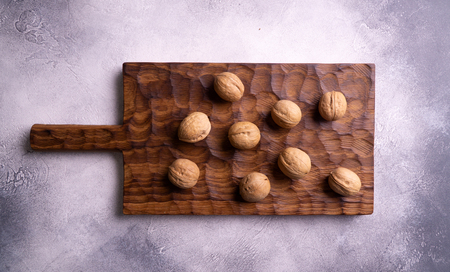 Whole walnuts on wooden carved board, top view. Healthy nuts and seeds composition.の写真素材