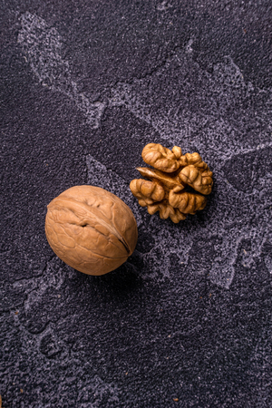 Walnut kernel and whole walnut on blue slate surface. Healthy nuts and seeds composition.の写真素材