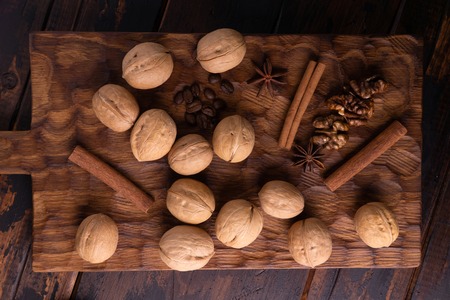 Walnuts, cinnamon, star anise, and coffee beans on wooden cutting board. Nuts and spices on the table. Food composition, top view.の写真素材