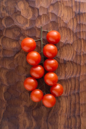 Fresh tomatoes on carved wooden cutting board. Top view with copy space.の写真素材