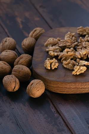 Cracked and whole walnuts on cutting board and wooden table, side view. Healthy nuts and seeds composition.の写真素材