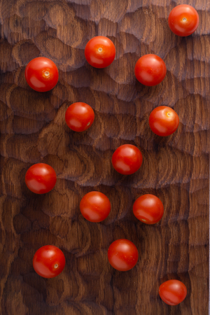 Fresh tomatoes on carved wooden cutting board. Top view with copy space.の写真素材