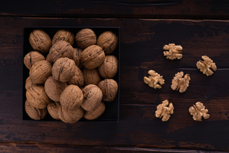 Whole and cracked walnuts on a square plate on wooden table, top view. Healthy nuts and seeds composition.の写真素材