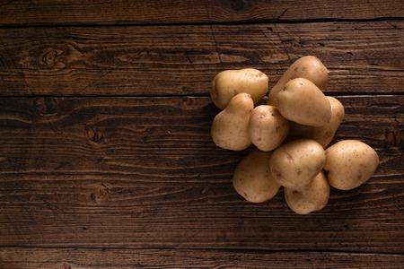 Heap of fresh potatoes on rustic wooden surface. Organic food, carbs, tubers.の写真素材