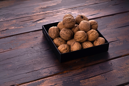 Whole walnuts on a square plate on wooden table, side view. Healthy nuts and seeds composition.の写真素材