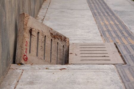 Sewage drain with open concret grate on the sidewalk, sewer.