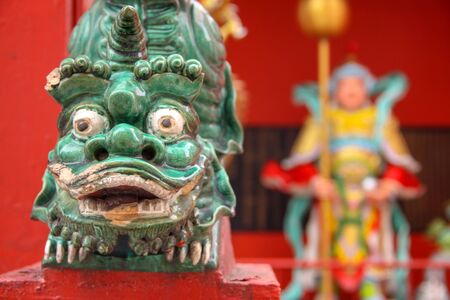 Close-up of traditional Chinese art statue animal head with a blurry background of Chinese temple. Green dragon head on vivid background.の写真素材