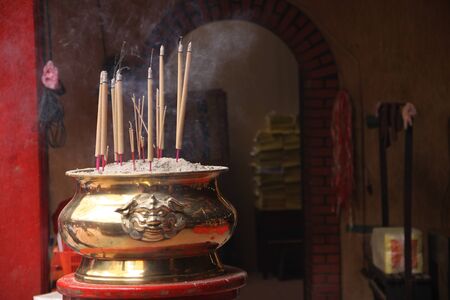 Incense sticks burning in metal burner, buddhist pray, Buddha worship in Thai or Chinese temple.の写真素材