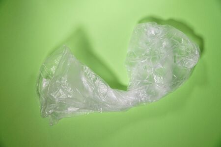 Empty crumpled plastic bag on green background. Concept of stop plastic pollution, global warming, recycling plastic, plastic free.の写真素材