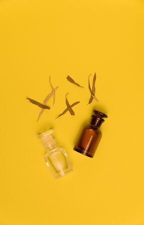 Two empty vials and dried grass blades on yellow background.の写真素材