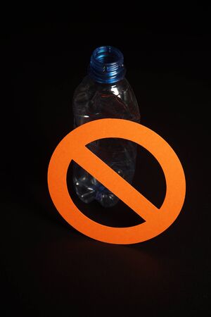 Empty blue plastic bottle in a stop sign on black background. Concept of stop plastic pollution, recycling plastic, plastic free.の写真素材
