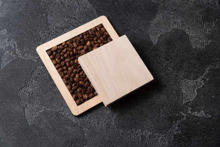Coffee beans in wooden box on a dark background.
