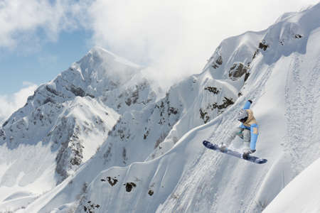 Flying snowboarder on mountains. Extreme sport, snowboarding.の写真素材