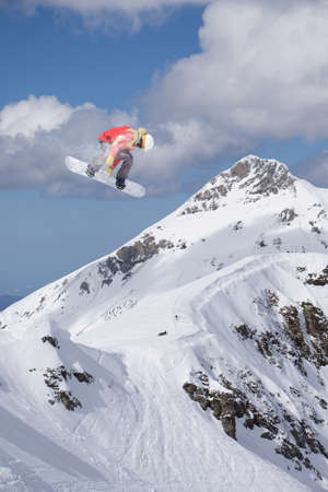 A jumping snowboarder in the mountains. Snowboarding, winter extreme sport.の写真素材