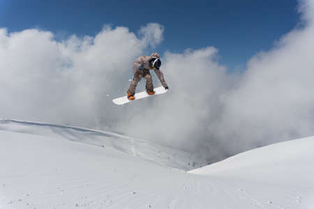 A jumping snowboarder in the mountains. Snowboarding, winter extreme sport.の写真素材