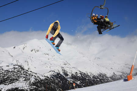 A jumping snowboarder in the mountains. Snowboarding, winter extreme sport.の写真素材
