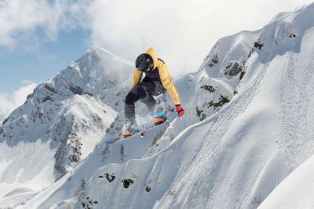 A jumping snowboarder in the mountains. Snowboarding, winter extreme sport.の写真素材