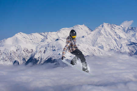 A jumping snowboarder in the mountains. Snowboarding, winter extreme sport.の写真素材