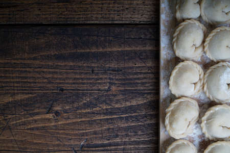 Meat or vegeterian dumplings, pelmeni on a wooden board. Russian national food. Close up top view with copy space.の写真素材