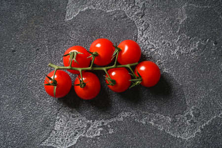 Ripe cherry tomatoes on a branch on a concrete background. Top view, copy space.の写真素材
