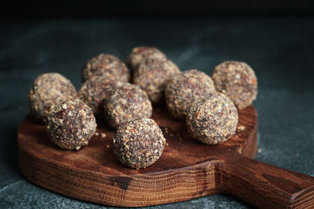 Healthy homemade energy balls on wooden plate. Vegan candies, sweets made of nuts and dates.の写真素材