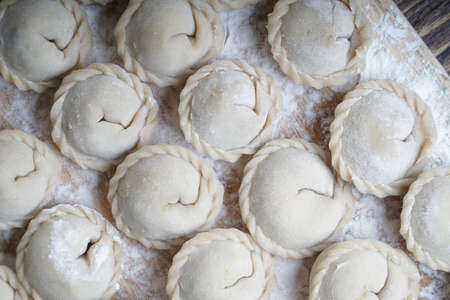 Meat or vegeterian dumplings, pelmeni on a wooden board. Russian national food. Close up top view.の写真素材