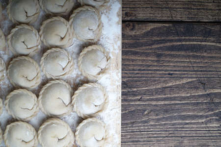 Meat or vegeterian dumplings, pelmeni on a wooden board. Russian national food. Close up top view with copy space.の写真素材