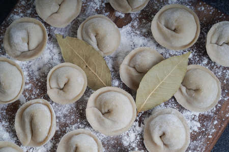 Meat or vegeterian dumplings, pelmeni on a wooden board. Russian national food. Close up top view.の写真素材