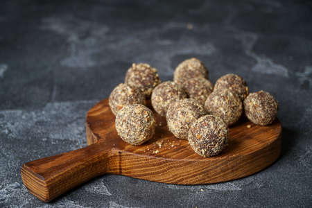 Healthy homemade energy balls on wooden plate. Vegan candies, sweets made of nuts and dates.の写真素材