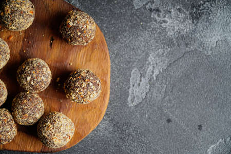 Healthy homemade energy balls on wooden plate. Vegan candies, sweets made of nuts and dates.の写真素材