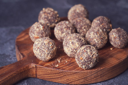 Healthy homemade energy balls on wooden plate. Vegan candies, sweets made of nuts and dates.の写真素材