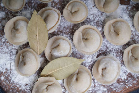 Meat or vegeterian dumplings, pelmeni on a wooden board. Russian national food. Close up top view.の写真素材