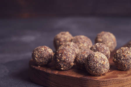 Healthy homemade energy balls on wooden plate. Vegan candies, sweets made of nuts and dates.の写真素材