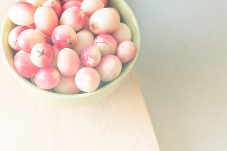 Carunda ( Karonda ) in green bowl and yellow wall backgroundの写真素材
