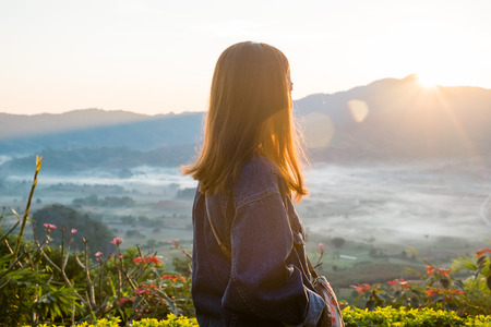 Young woman watching sunrise high in the mountain at Phu Lung ka,Thailandの写真素材