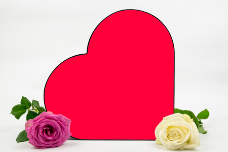 a red heart with two roses on the side, a white rose and a pink rose. the heart has space to put on your own text. Can be used as a backgroundの写真素材