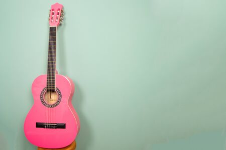 pink guitar in front of a green background. With the extra space on the right you can put your own text.の写真素材