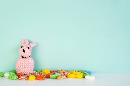 stuffed bunny toy with colored candy in front of a colored background, with space next to itの写真素材