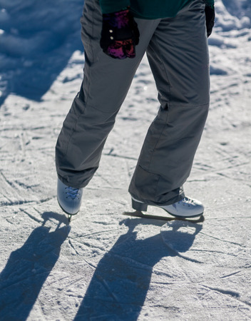Skating on frozen mountain lake, sun and funの写真素材