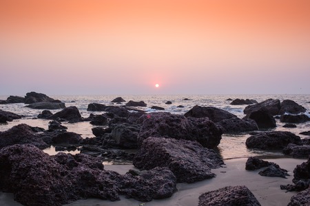 Tropical beach with rock at sunset - nature background