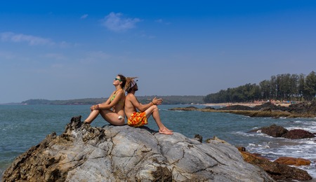 Beach travel banner - romantic couple relaxing on vacation enjoying ocean view together sitting in the sand embracing and hugging. Beautiful young multiracial coupleの写真素材