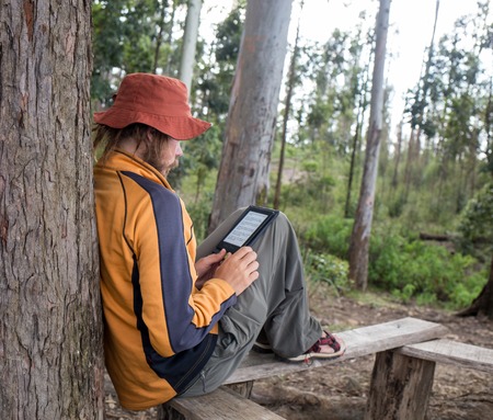 Young Man Traveler with backpack reading book and writing notes outdoor mountains on background Summer vacations and Lifestyle conceptの写真素材
